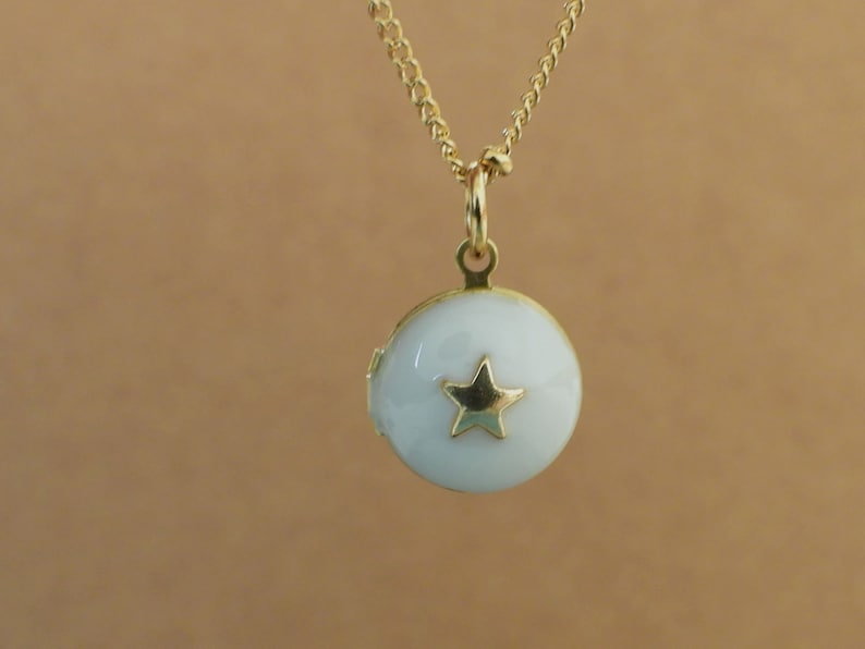 May include: A gold chain necklace with a white locket pendant featuring a gold star design.