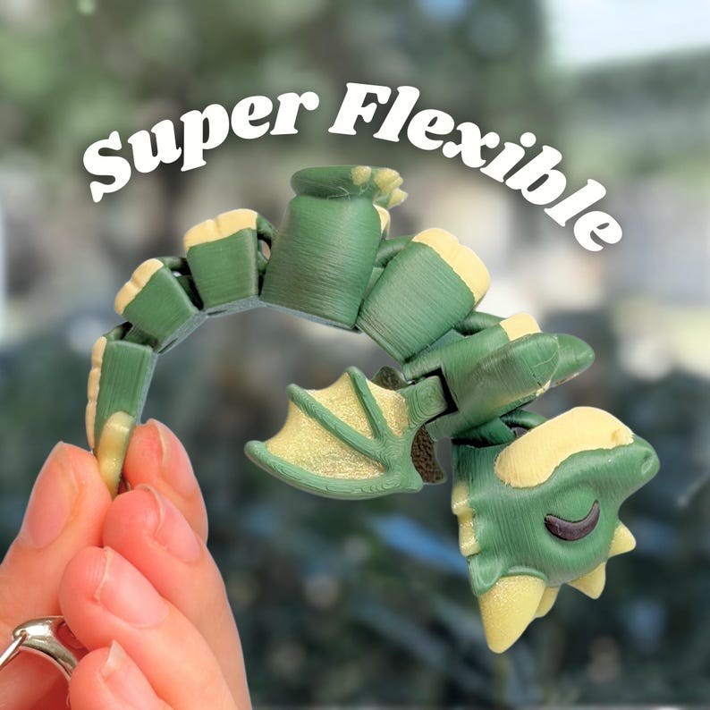 May include: A green and yellow articulated dragon toy is held in a hand, showcasing its flexibility. The dragon has a detailed design with wings and a smiling face. The text "Super Flexible" is displayed above the toy.