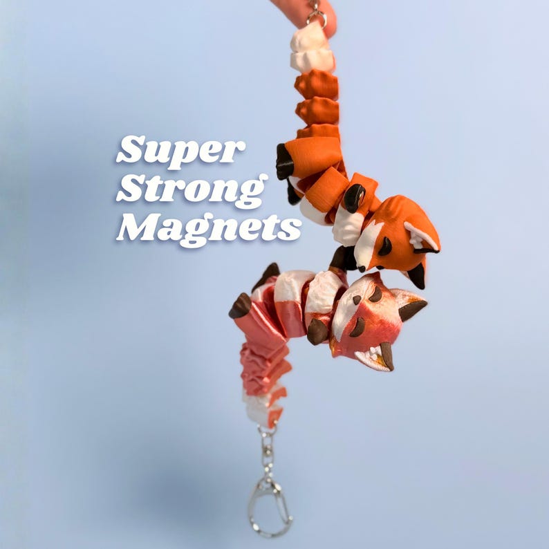 Classic Orange and Golden Hour fox keychains held together magnetically, paws clasped in a hug against a light blue background. Golden Hour shimmers from pink to warm orange while Classic is bold bright orange. Their paw magnets hold them together strongly. Fox keychain magnetic paws best friend keychain 3D printed fidget matching keychains couple keychain fox lover gift cute fox bag charm