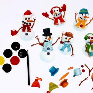 May include: A selection of snowman craft supplies. The snowmen are adorned with hats, scarves, and earmuffs. The image includes paint, brushes, and extra snowman components like carrot noses and twig arms. The snowmen are set against a white backdrop.