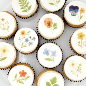 May include: A white ceramic mug with a black handle and the text "But First, Coffee" in a black, handwritten-style font. The mug is on a white surface.