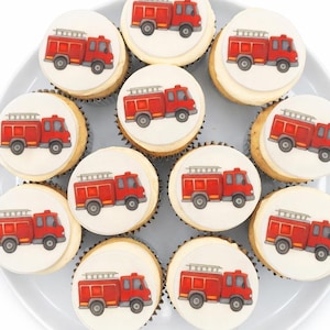 May include: A dozen cupcakes arranged on a white plate. Each cupcake has a white frosting base and a circular edible image of a red fire truck. The fire trucks have black tires and silver ladders. The cupcakes are a dessert.