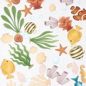 Könnte beinhalten: Aquarellillustrationen von Meereslebewesen, darunter Fische, Seepferdchen, Korallen und Muscheln. Das Kunstwerk zeigt ein Lineal mit Zollmaßen. Die Meereslebewesen sind in Blau-, Orange-, Gelb- und Grüntönen gehalten.