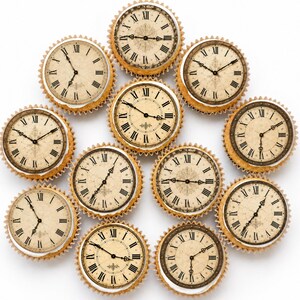 May include: A collection of eleven cupcakes arranged in a circular pattern, each topped with a circular edible image of a vintage clock face featuring black Roman numerals, ornate hands, and a distressed beige background with a paper-like texture.