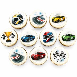 May include: Ten round cupcakes featuring edible toppers with racing themes, including yellow, blue, red, and green race cars, a gold trophy, chequered flags, racing helmets, and a curved track with red and white kerbing on a white background.