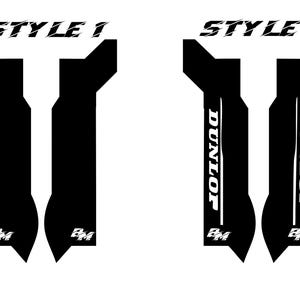 May include: Two black and white motorcycle decals. Style 1 features two black shapes with the text "STYLE 1" above. Style 2 has the word "DUNLOP" in white on each black shape, with "STYLE 2" above. The decals have the letters "BM" at the bottom.
