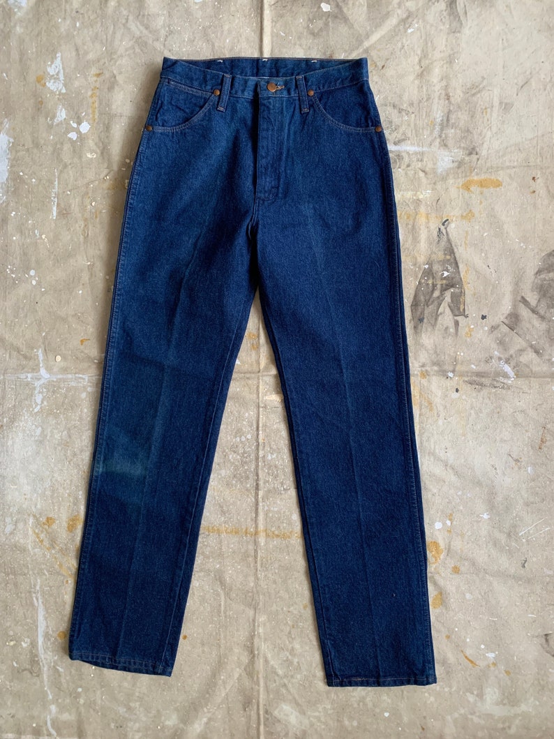 Puede incluir: Un par de pantalones vaqueros de mezclilla azul oscuro con corte recto. Los pantalones tienen un estilo cl&aacute;sico de cinco bolsillos y cierre de bot&oacute;n.