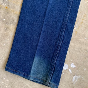 Puede incluir: Primer plano del dobladillo inferior de un par de pantalones vaqueros de mezclilla azul. Los vaqueros tienen una pierna recta y un ajuste cl&aacute;sico.