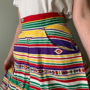 May include: A colorful striped skirt with a geometric pattern. The skirt has a high waist and two pockets. The skirt is made of a lightweight fabric and is perfect for summer.