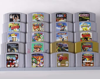 May include: A collection of Nintendo 64 video game cartridges, featuring titles like "Mario Kart 64", "The Legend of Zelda", and "Pokémon Stadium". The cartridges are arranged in a gray display rack, showcasing the colorful game box art.