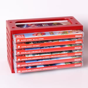 May include: A red wooden game cartridge holder with a stack of Nintendo Switch game cases. The game cases are red and white with game titles such as "Super Mario 3D All-Stars" and "Xenoblade Chronicles 2". The holder has a rectangular opening at the top.