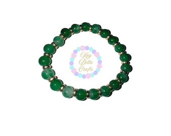 May include: A green beaded bracelet with gold accents. The beads are round and have a marbled pattern.