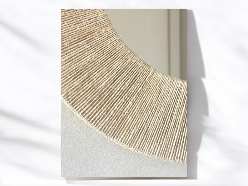 May include: A rectangular mirror featuring a semi-circular frame section wrapped in natural beige jute twine. The lower portion of the mirror surface is framed by a textured, off-white matte border that contrasts with the reflective glass.