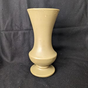 May include: A light brown ceramic vase with a flared top and a rounded base. The vase has a smooth, glossy finish.