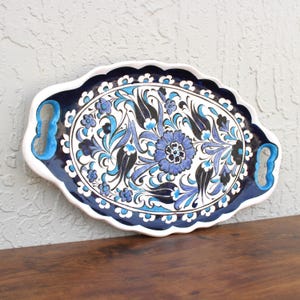 Side view of handpainted ceramic serving tray highlighting its curved edge and floral design.