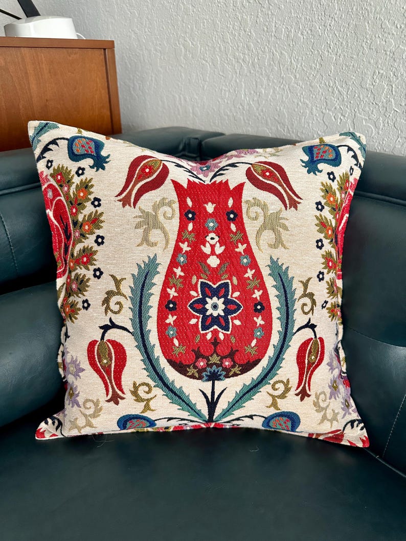 Puede incluir: Una almohada decorativa con un patr&oacute;n floral con tulipanes rojos, azules y verdes sobre un fondo crema.