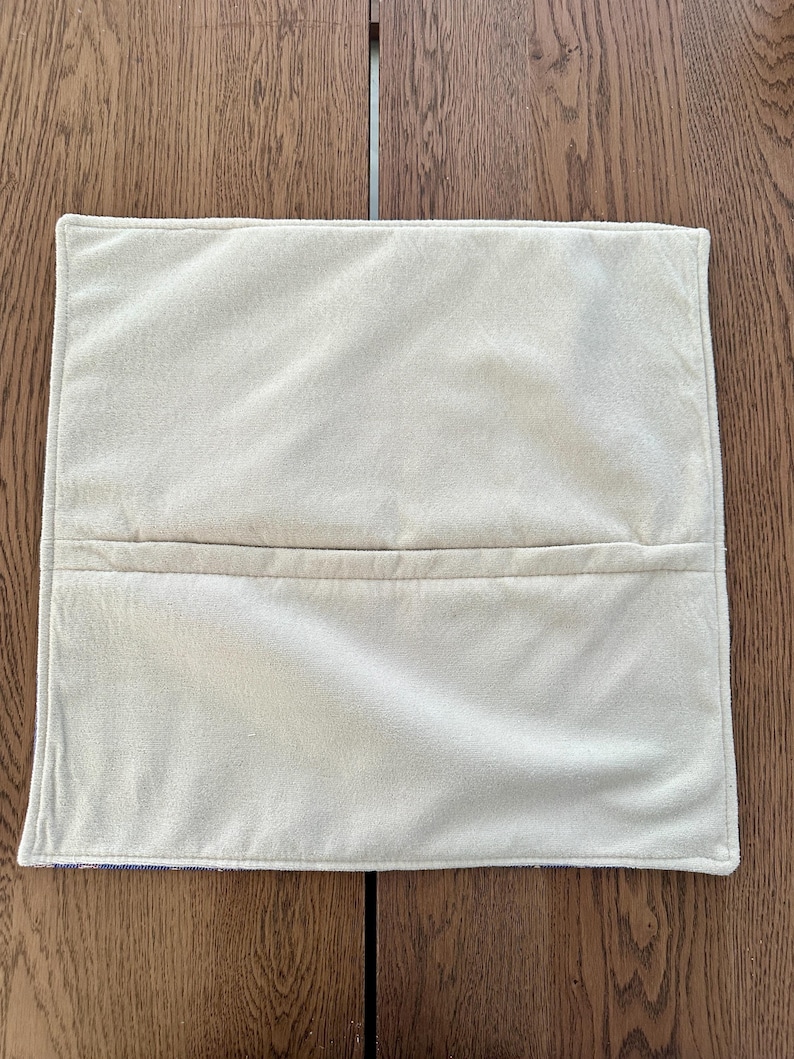 Puede incluir: Una funda de almohada blanca lisa con una costura en el centro. La funda de almohada est&aacute; hecha de una tela suave y mullida.