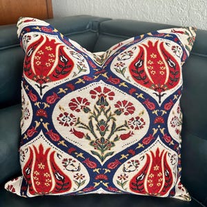 Puede incluir: Una almohada decorativa con un dise&ntilde;o tradicional turco en colores rojo, blanco, azul y verde. La almohada tiene un patr&oacute;n floral con tulipanes estilizados y otros motivos florales.