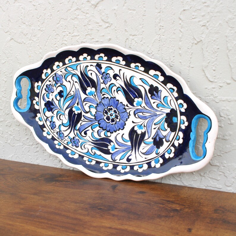 Angled view of ceramic tray showing intricate blue floral patterns and cutout handles.