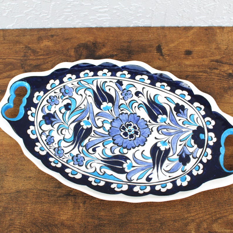 Close-up of handpainted blue and black floral detailing on oval ceramic tray.