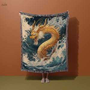 May include: A woven tapestry blanket depicting a golden dragon in a sea of blue and white waves. The dragon is highly detailed, set against a dark blue backdrop. The blanket has a fringed border.