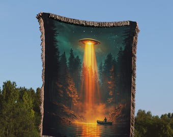 May include: A woven tapestry depicting a dark green forest scene with a glowing orange UFO hovering above a lake. A lone figure in a boat can be seen in the water below the UFO.