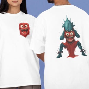 Puede incluir: Camisetas blancas con diseños de monstruos de dibujos animados. Una camiseta tiene un pequeño monstruo rojo en el pecho, la otra una ilustración de monstruo más grande y detallada en la espalda. Los monstruos tienen dientes afilados y una expresión amenazante.