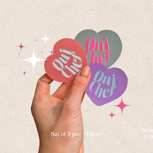 May include: Set of three pastel pink, purple, and gray heart-shaped stickers with the text "Oui Chef" in white lettering.