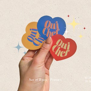 May include: Set of three heart-shaped stickers with the text "Oui Chef" in gold lettering. The stickers are blue, yellow, and red.
