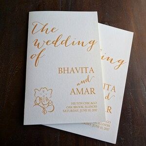 May include: Wedding invitation for Bhavita and Amar, featuring a gold elephant illustration and the text "The Wedding of Bhavita and Amar, Hilton Chicago, Oak Brook, Illinois, Saturday, June 10, 2017."