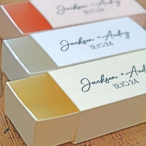 May include: Three white boxes with sliding lids. The boxes are labeled with the names "Jackson + Audrey" and the date "12.10.24".