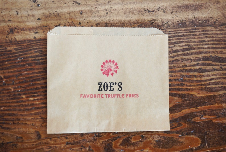 Op de afbeelding: Een bruine papieren zak met een rood en zwart logo met de tekst "ZOE'S FAVORITE TRUFFLE FRIES".