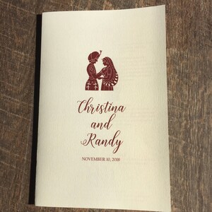 May include: A wedding program with a burgundy illustration of a couple holding hands. The text reads "Christina and Randy" with the date "November 10, 2018" below.