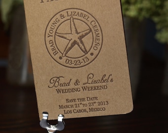 Puede incluir: Una tarjeta de guardar la fecha de estilo pasaporte en papel marrón con un diseño de estrella de mar y el texto "Brad & Lizabel's Wedding Weekend" y "Save the Date March 21st to 23rd 2013 Los Cabos, Mexico".