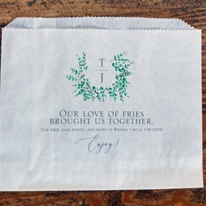 Op de afbeelding: Een witte papieren zak met een groen bladerontwerp en de tekst "Our love of fries brought us together. Our first date ended late night at Weiner Circle 7-18-2009. Enjoy!"