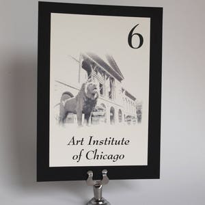 May include: Black and white photo of the Art Institute of Chicago with the lion statues in front. The table number is 6.