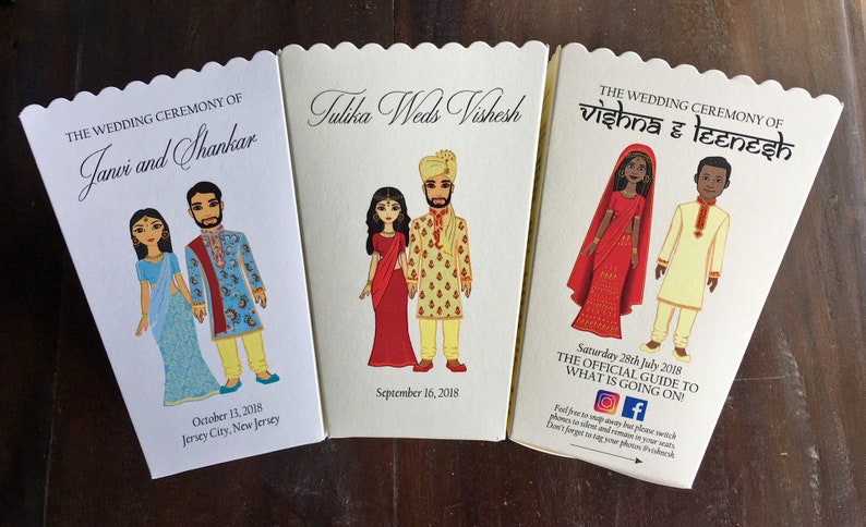 以下が含まれることがあります： インドの伝統的な衣装を着たカップルが描かれた、結婚式のお祝いの招待状が3枚。招待状は、波打つ縁取りのある白い厚紙に印刷されています。招待状には、カップルの名前、式典の日時、場所が記載されています。