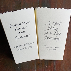 May include: Two off-white paper popcorn boxes with scalloped top edges. The left box reads "Thank You Family and Friends" with "Wendy & Frank" and "August 18, 2018" below. The right box reads "A Sweet Ending To a New Beginning." with "Tricia and Kevin" and "May 4 2018" below.