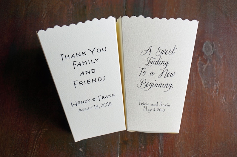 May include: Two off-white paper popcorn boxes with scalloped top edges. The left box reads "Thank You Family and Friends" with "Wendy & Frank" and "August 18, 2018" below. The right box reads "A Sweet Ending To a New Beginning." with "Tricia and Kevin" and "May 4 2018" below.