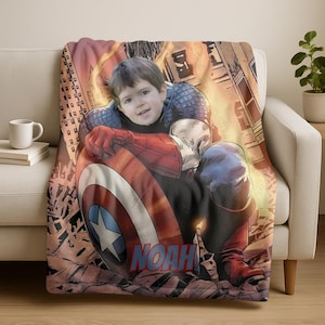 May include: A personalized Captain America blanket featuring a child's face integrated into the superhero's costume. The blanket showcases a vibrant comic book style background with the name "NOAH" in bold letters. The blanket is draped over a white sofa.