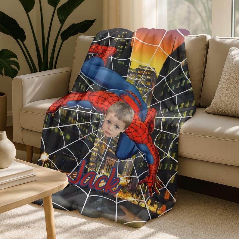 Puede incluir: Una manta personalizada de Spider-Man con el superh&eacute;roe en una pose din&aacute;mica contra un paisaje urbano. La manta es predominantemente roja y azul, con un dise&ntilde;o de telara&ntilde;a blanca. El nombre "Jack" est&aacute; escrito en una fuente estilizada.