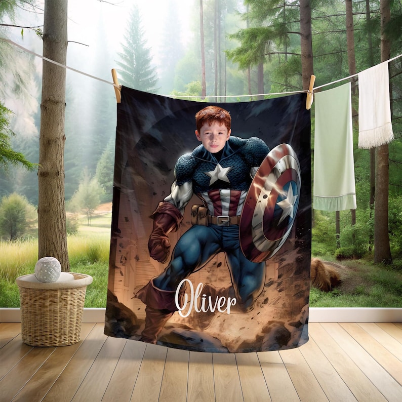May include: A Captain America themed blanket featuring a young boy in the Captain America costume, holding a shield. The blanket is hanging on a clothesline with other items. The name "Oliver" is written on the blanket.