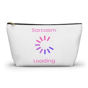 May include: White cosmetic bag with a black zip and gold pull. The bag has the words "Sarcasm Loading" in pink and a loading symbol in pink and purple.