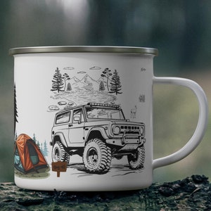 May include: White enamel camping mug featuring a black and white illustration of a 4x4 vehicle, a tent, and a mountain scene. The mug has a silver rim and a white handle. The design includes the text "Camp Life".