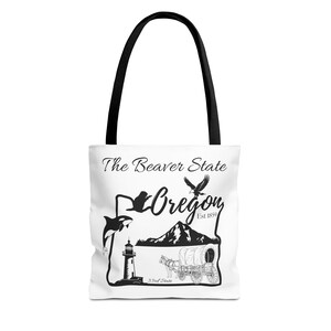 May include: White tote bag with black handles featuring a black and white graphic of Oregon state symbols. The design includes a whale, eagle, mountains, lighthouse, and a covered wagon, with the text "The Beaver State" and "Oregon".