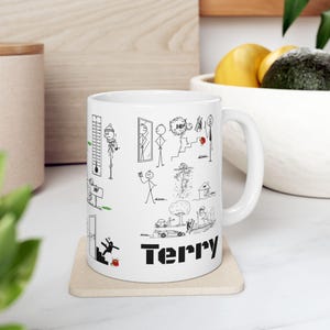 Puede incluir: Taza de cerámica blanca con ilustraciones de figuras de palo negras y el nombre "Terry" impreso en letras negras en negrita. La taza presenta varias escenas humorísticas de figuras de palo.