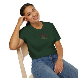 Puede incluir: Una camiseta verde oscuro con un pequeño diseño bordado de rosas rojas en la parte delantera.