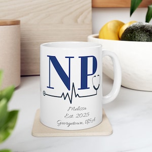 May include: White ceramic mug with navy blue "NP" lettering, a stethoscope graphic, and a heartbeat line design. The mug is personalized with the name "Melissa", the year "2025", and "Georgetown, USA".