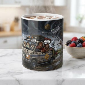May include: A white ceramic mug featuring a colorful cartoon illustration of a van filled with various creatures driving through a storm. The van has text including "The Cryptid Chasers," "Drive, kitty, drive!," "It's a whirlwind!," "Squatch Watch," and "Nebraska or Bust."