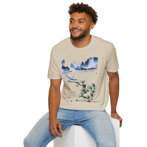 May include: A beige t-shirt with a blue and white landscape print featuring a bird, bamboo, and the text "山水之间"
